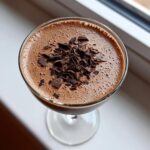 Overhead view of a creamy chocolate martini cocktail garnished with dark chocolate shavings.