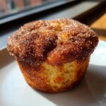 A close-up of a single cinnamon sugar french toast muffin topped with sparkling cinnamon sugar crystals.
