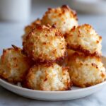A stack of golden brown coconut macaroons recipe treats piled on a small white plate.