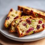 Close-up of thick slices of cranberry pistachio biscotti showing dried cranberries and bright green pistachios.