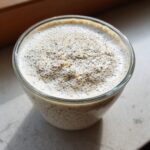 Close-up of creamy, high-protein chia pudding topped with visible chia seeds in a clear glass.