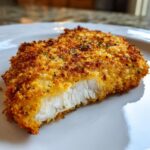 Close-up of a perfectly cooked air fryer chicken breast with a golden, crispy breading and moist white interior.