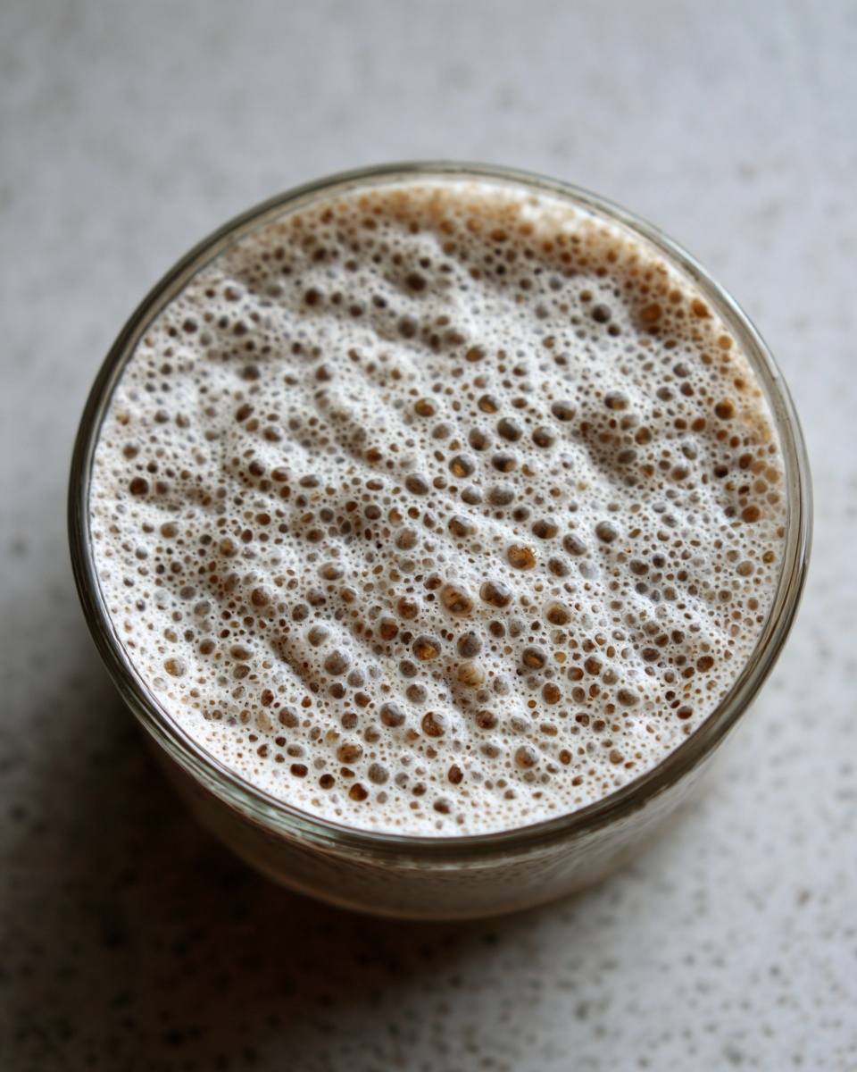 Overhead view of a glass filled with a blended chia pudding mixture topped with thick, creamy foam.