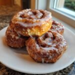 Four golden brown tiktok cinnamon rolls with half and half drizzled with white icing stacked on a white plate.