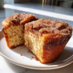 A gluten free cinnamon sugar french toast muffin cut in half, showing the soft interior and sugary topping.