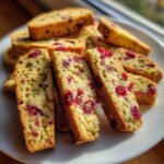 A stack of freshly baked gluten free cranberry pistachio biscotti slices showing bright red cranberries and green pistachios.