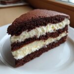 Close-up of a decadent slice of Italian love cake featuring dark chocolate layers and thick white cream filling.