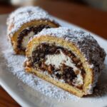 Close-up of sliced italian nut roll cookies with cream cheese dough, dusted heavily with powdered sugar.
