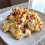 A scoop of creamy jalapeno popper chicken salad high protein topped with shredded cheddar and crispy bacon bits.