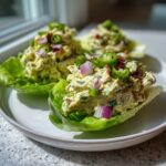 Three servings of jalapeno popper chicken salad nestled in crisp lettuce cups, topped with jalapeño slices and red onion.