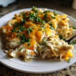 A serving of creamy keto chicken pot pie casserole topped with melted cheddar cheese and fresh parsley.
