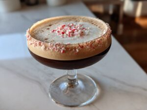 A rich peppermint espresso martini garnished with a crushed candy cane rim and topping.