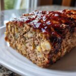 Close-up of a moist slice of smoked stove top stuffing meatloaf topped with a shiny brown glaze.
