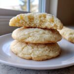Close-up of three stacked soft sugar cookies, one broken open to show the texture.