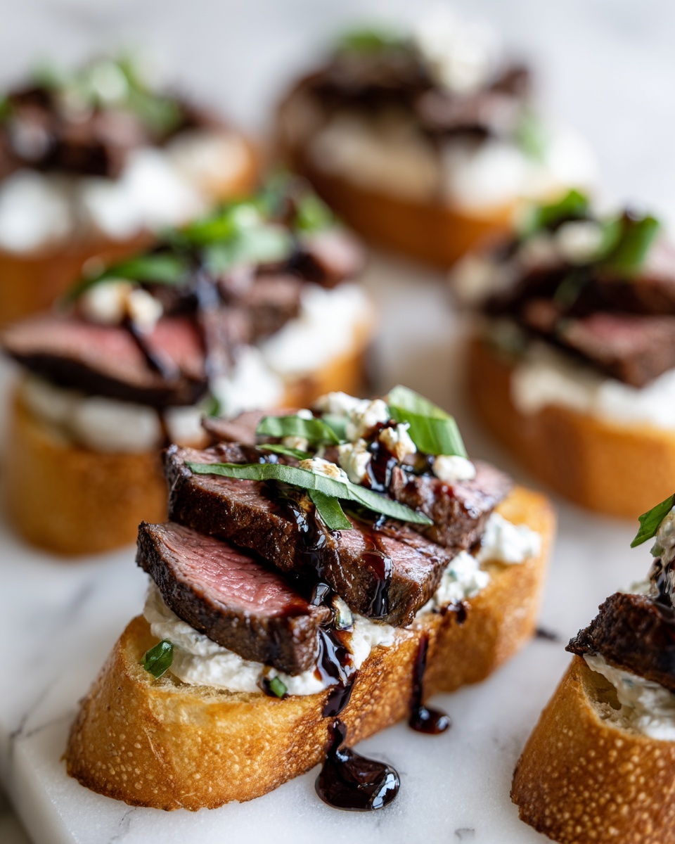 Close-up of gourmet steak crostini topped with medium-rare steak, creamy cheese, and balsamic glaze.