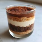 Close-up of layered tiramisu chia pudding featuring dark chia seeds, creamy filling, and cocoa powder topping.