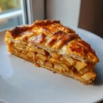 Close-up of a flaky slice of apple galette showing cinnamon-spiced apple filling and a golden lattice crust.