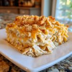 A generous square serving of cheesy chicken noodle casserole topped with melted cheddar and crunchy breadcrumbs.