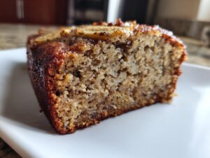 Close-up of a moist slice of cottage cheese banana bread almond flour, showing the dense crumb and caramelized top.