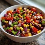 Close-up of a vibrant bowl of cowboy caviar recipe italian dressing mix with beans, corn, tomatoes, and peppers.