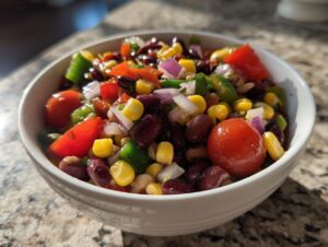 Close-up of a white bowl filled with colorful cowboy caviar recipe italian dressing ingredients like beans, corn, and tomatoes.
